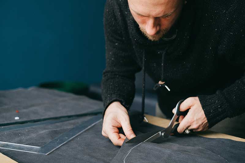 Fashion designer cutting fabric for unique pieces at a women’s clothing boutique.
