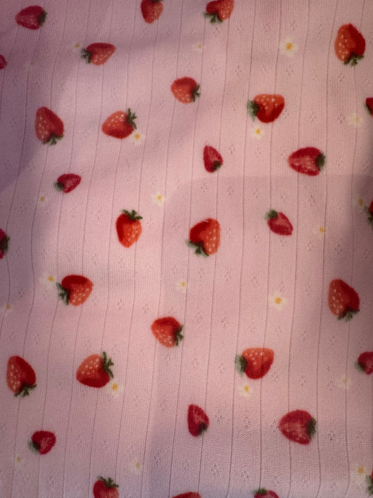 Pink fabric featuring colorful strawberry prints, perfect for summer styles at Sophie May Boutique.